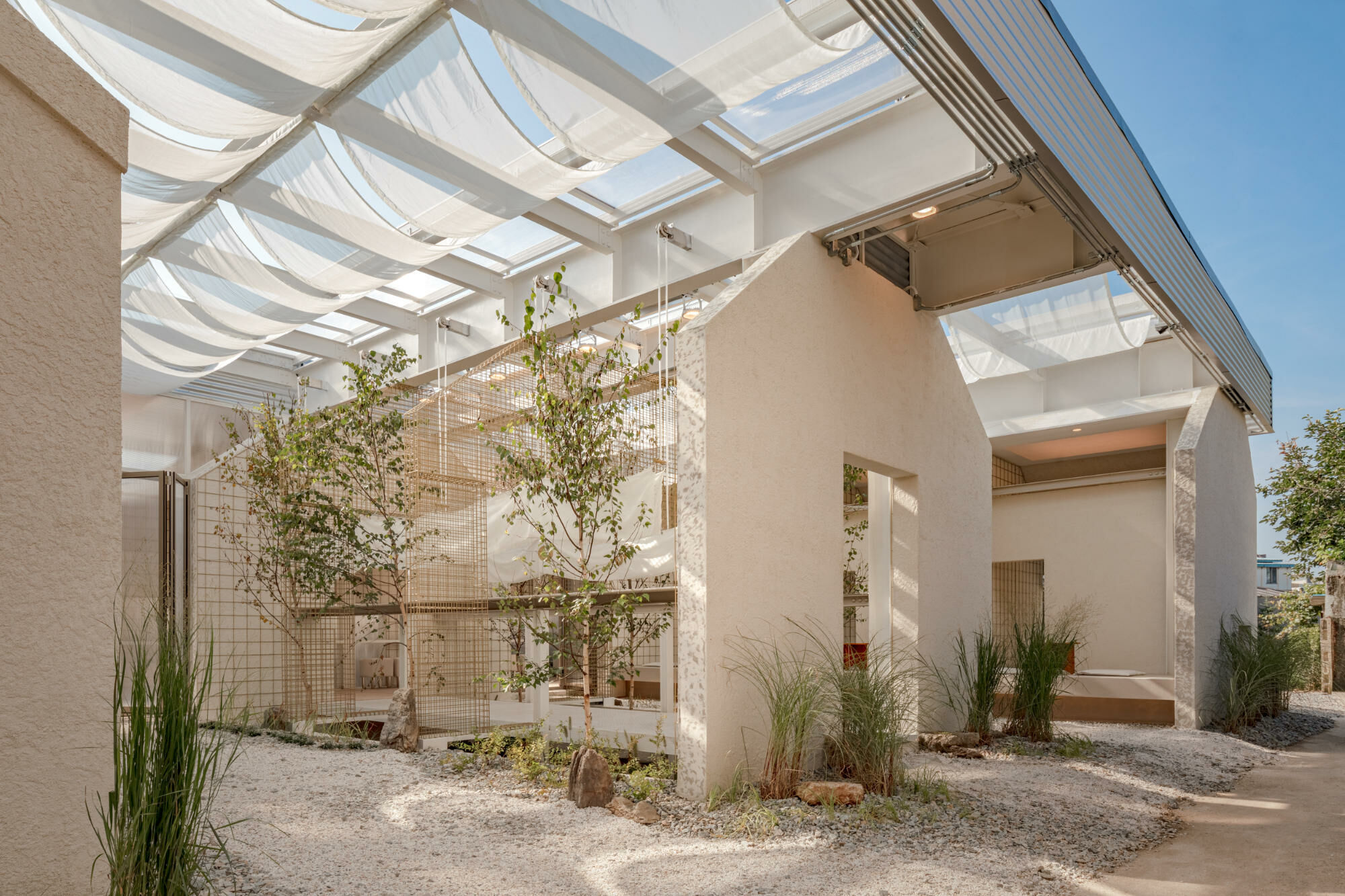 Das Architekturbüro one-aftr hat den kleinen Komplex aus drei Gebäuden mit einer Stahldachkonstruktion überspannt und zu einer Einheit gefasst..