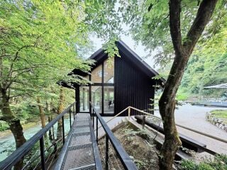 Der Neubau zwischen Wegeführung und Flussverlauf erstreckt sich in Nord-Süd-Richtung.