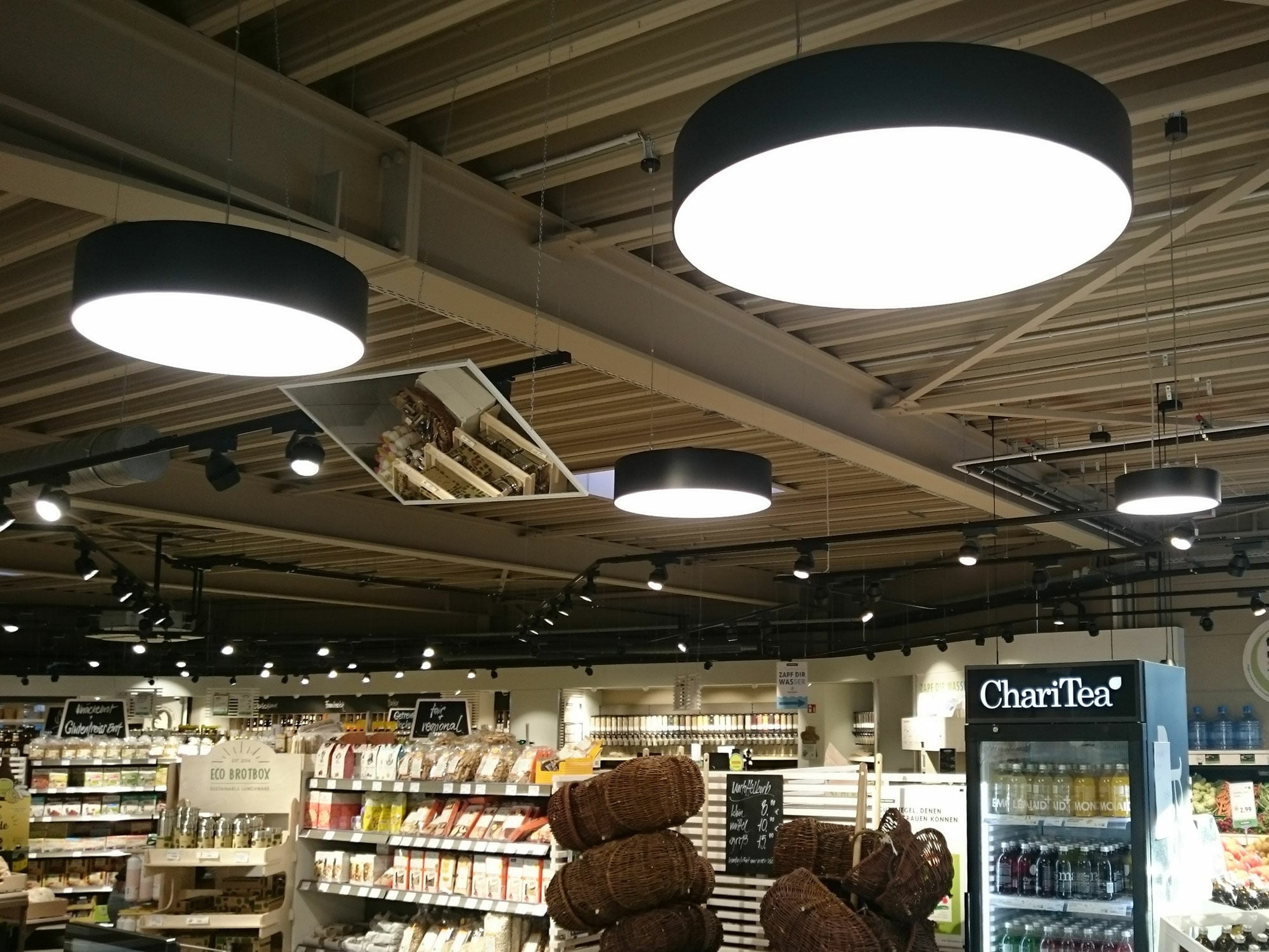 Auch Pendelleuchten mit Diffusor können ihr Licht breit streuen. Eine Grundbeleuchtung mit Pendelleuchten braucht eine sorgfältige Planung. Der Abstand der Leuchten und ihr Lichtkegel entscheidet, ob Flächen schattenfrei ausgeleuchtet sind oder ob Lichtinseln entstehen. Spots sorgen hier für die gezielte Warenausleuchtung.