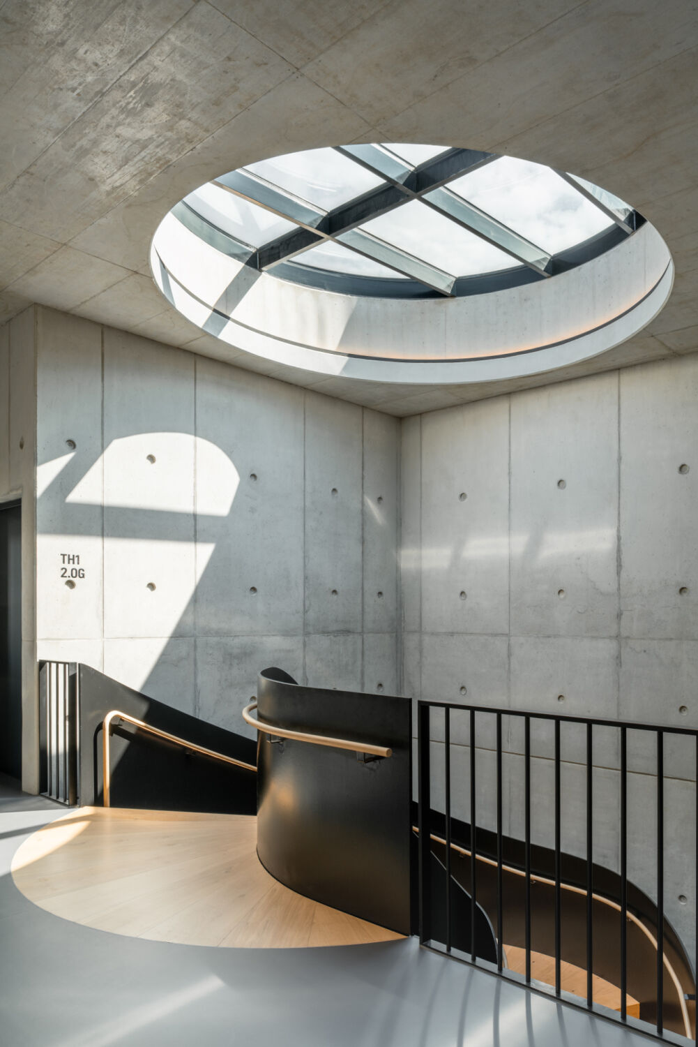 Über der Wendeltreppe bringt ein rundes Oberlicht Helligkeit in die Tiefe des Gebäudekerns.