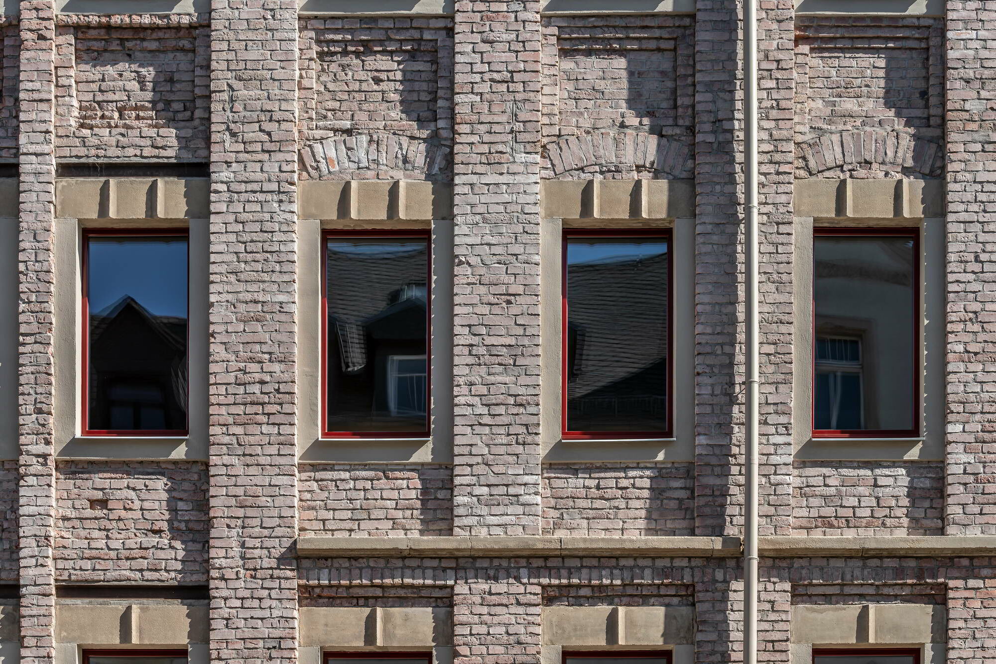 Die Unregelmäßigkeiten und Blessuren in der Straßenfassade wurden bei der Sanierung sichtbar belassen, die Fensteröffnungen allerdings mit akkuraten Faschen versehen, um die Fensterrahmen teils zu verstecken.