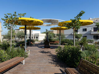 Knallgelbe Sonnenschirme stehen im Zentrum dieser begrünten Parkraumüberdachung in Malta.