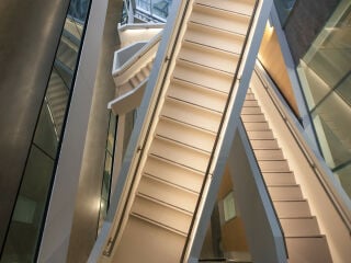 Der Neubau der HEC Business-School in Montreal zeigt sich einladend mit gläserner Fassade und breiter Eingangstreppe. Das Gebäude liegt am Hang; über diesen Südeingang gelangt man ins zweite Obergeschoss, dem oberen Erdgeschoss.