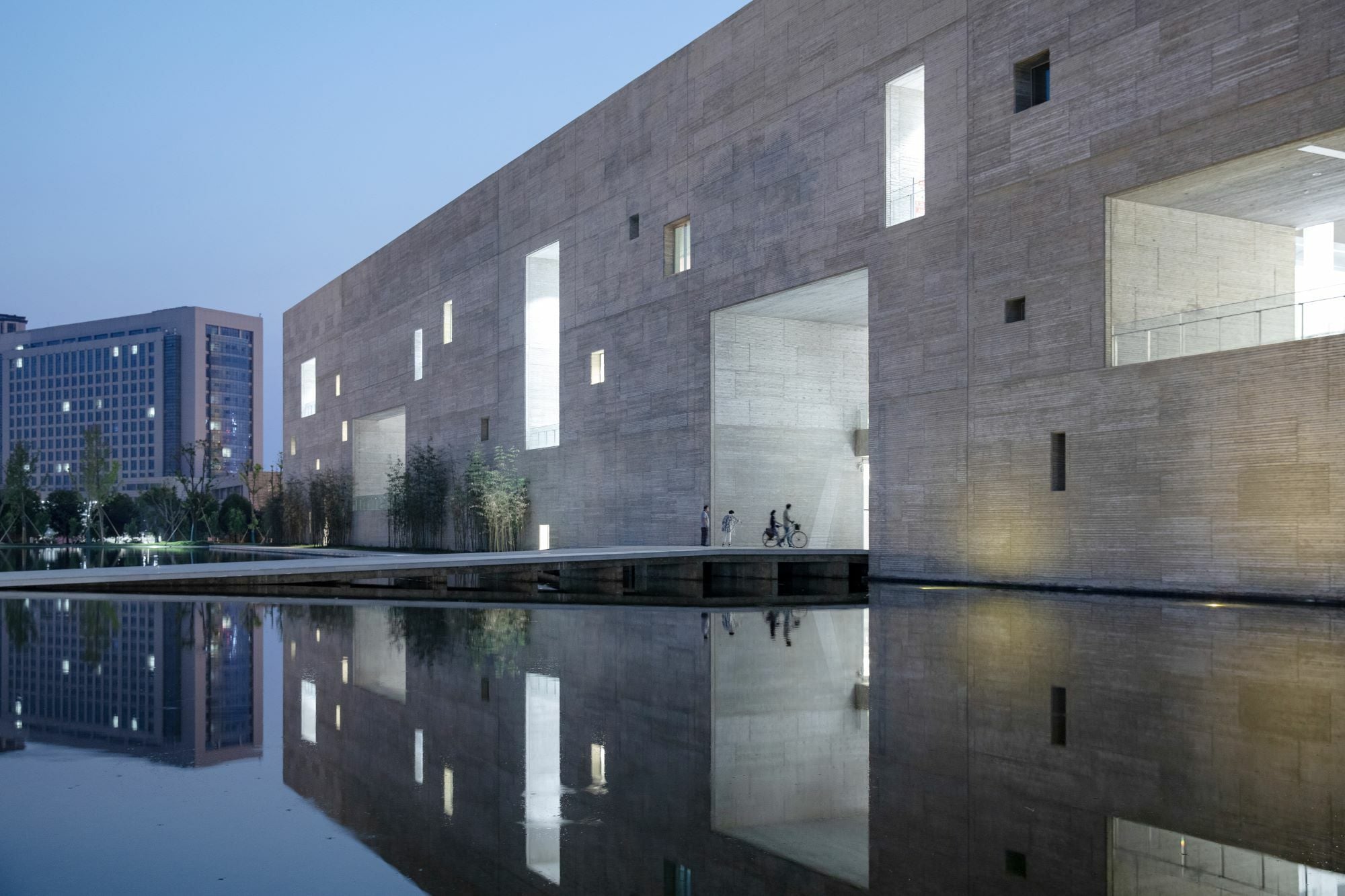 Wasserflächen umspielen das Bauwerk und reflektieren die hohen Außenwände, die einer antiken Stadtmauer nachempfunden sind. 