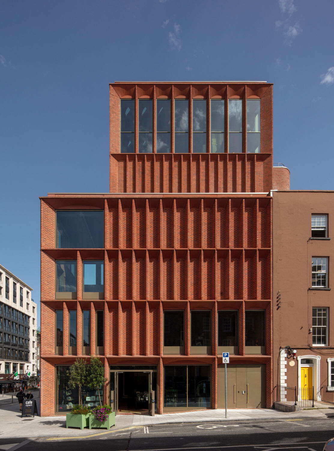 Gegliedert durch tiefe, vertikale Pfeiler und horizontale Sichtbetonelemente hat die Fassade eine skulpturale Anmutung. 