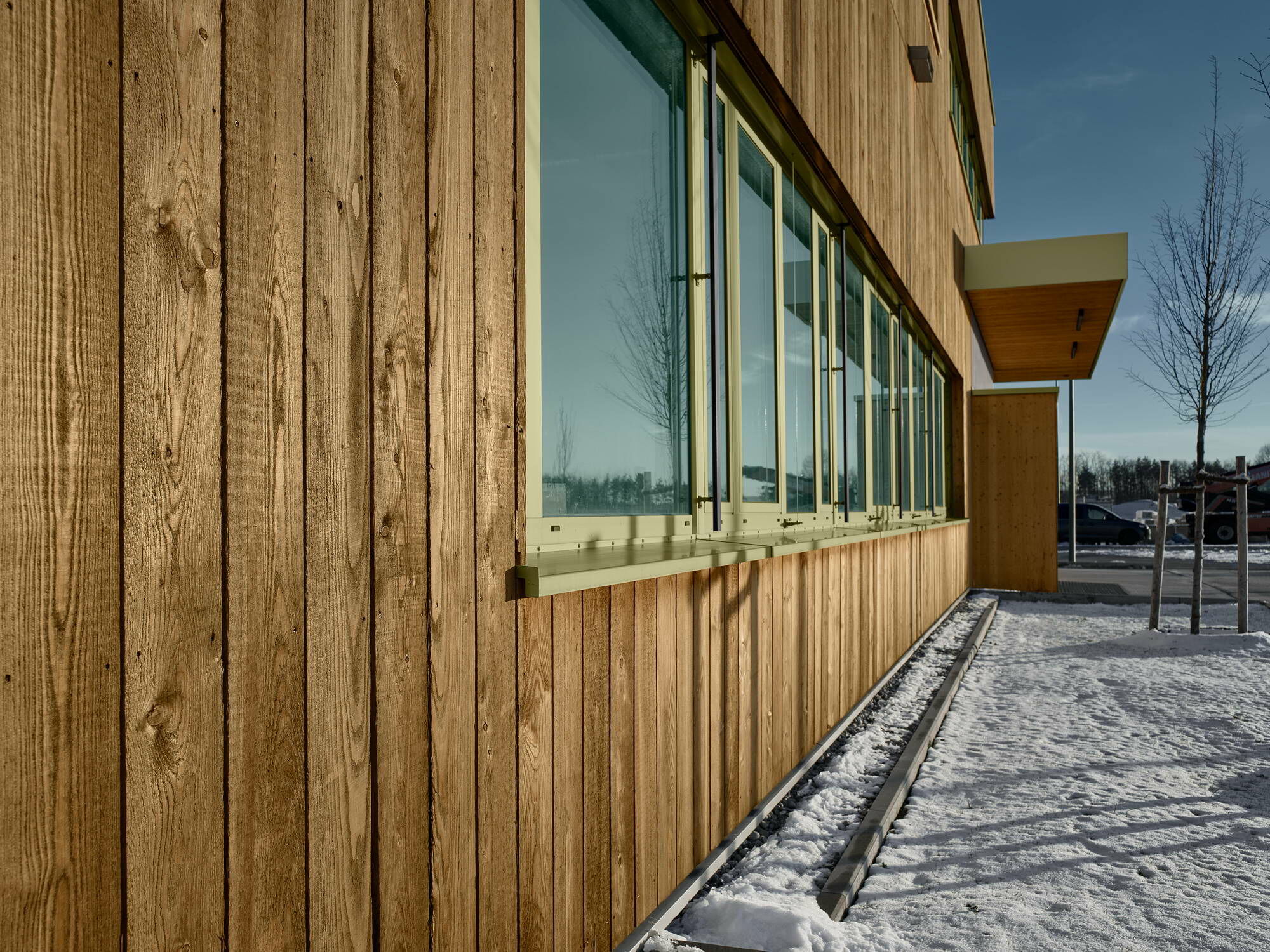 Die Fassade ist größtenteils mit unbehandeltem, heimischem Lärchenholz verkleidet, einige wenige Flächen bestehen aus Sichtbeton.