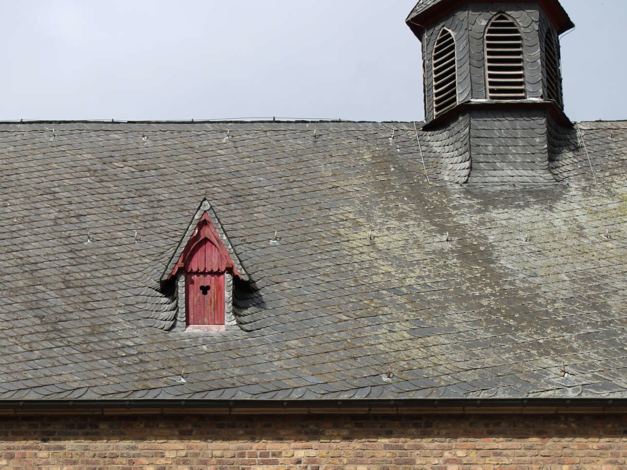 Satteldachgaube bei einem schiefergedeckten Kirchendach im Rhein-Sieg-Kreis