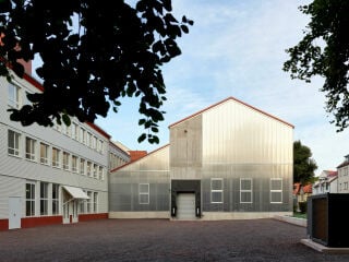Bestandsbau der Werkstätten (links) mit neuer Holzfassade und Fundus-Neubau mit transluzenter Polycarbonat-Hülle nach Plänen des Leipziger Büros Voigt