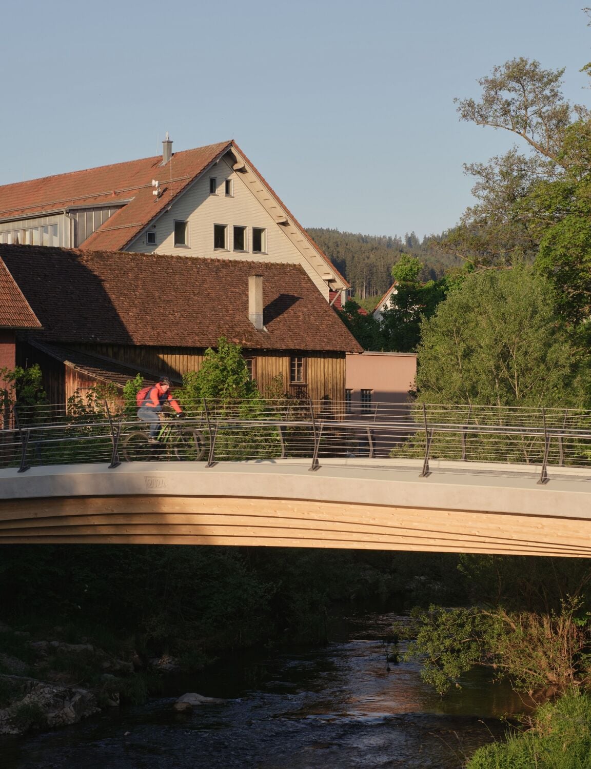 Die leicht geschwungene Brücke ist eine Hybridkonstruktion aus Holz und Beton.