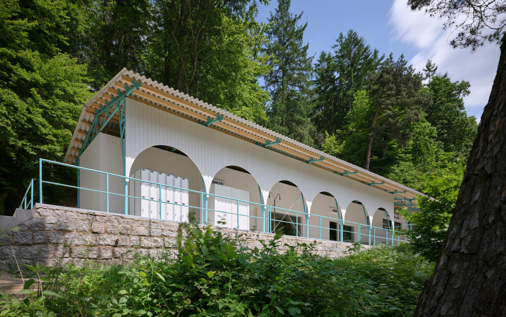 Die Holzrahmenkonstruktion aus CLT-Paneelen folgt den zwei Niveaus der vorhandenen Betonplatte und nimmt von Westen nach Osten die zentralen Funktionsbereiche auf: Lagerraum, WCs, eine Sauna mit Lounge-Bereich sowie einen Kiosk. 