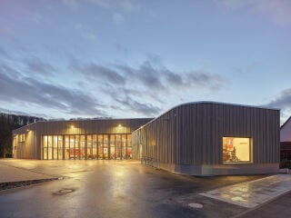 Eindruck in der Dämmerung: Vorplatz mit Blick auf das Schaufenster und die Fahrzeughalle