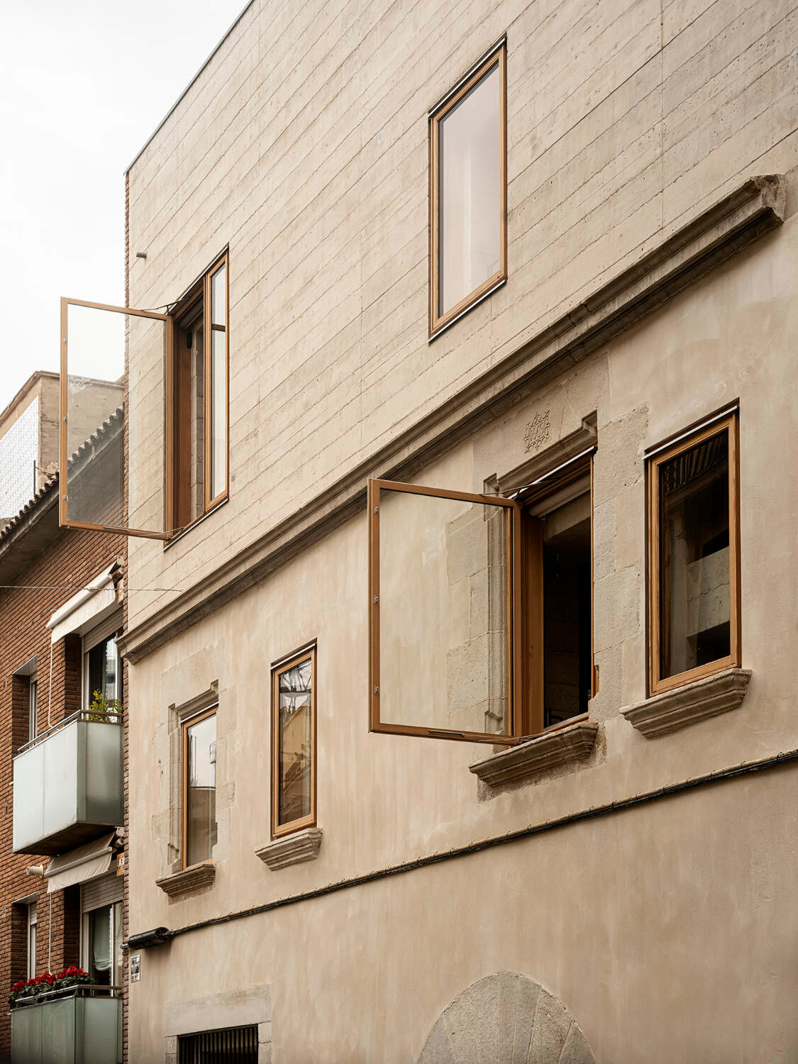 Zur Straße hin zeigen sich die erhaltene historische Fassade im Erdgeschoss und die schlichte Aufstockung.