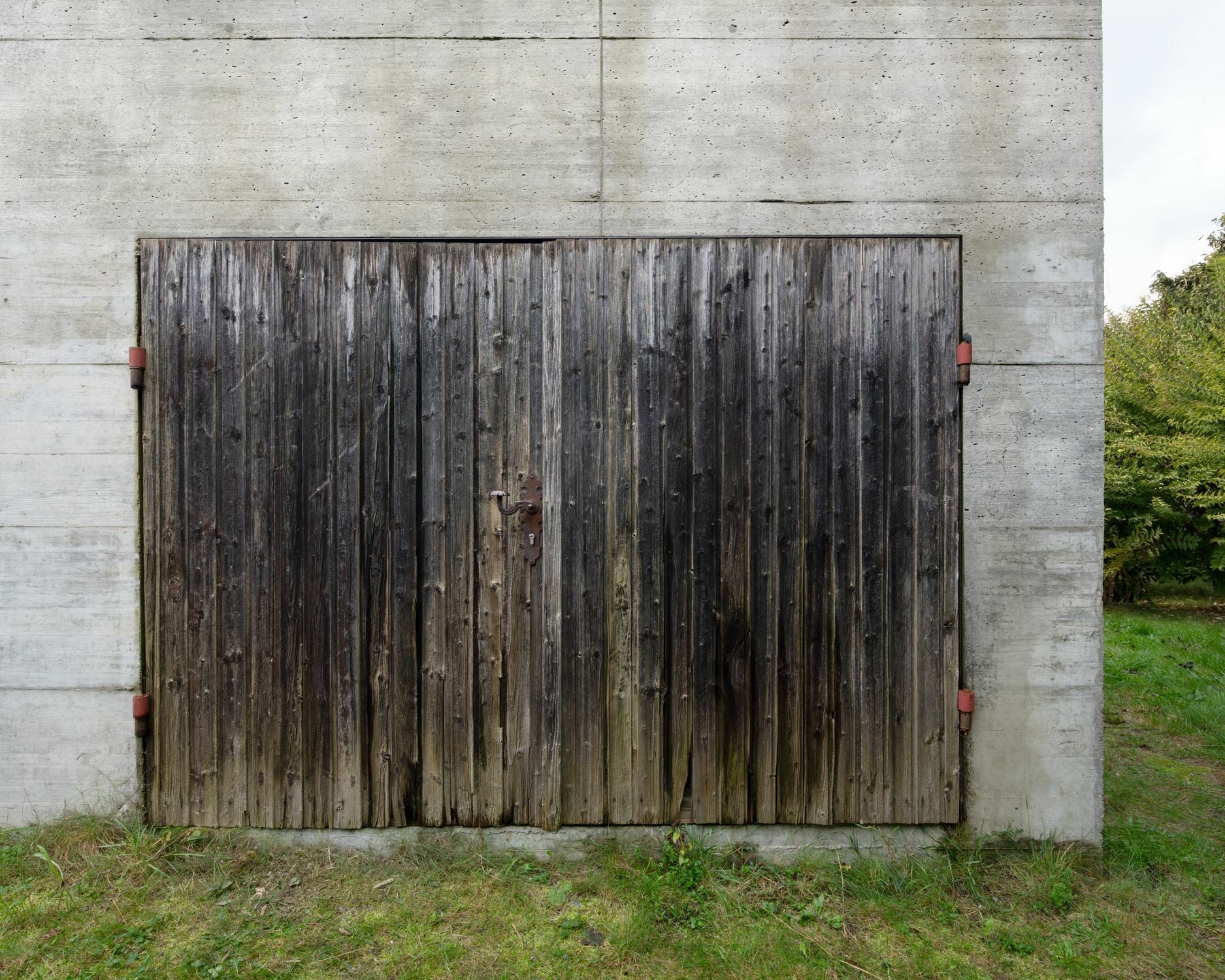An der Nordseite begrenzt ein wiederverwendetes, altes Garagentor die Öffnung des Kaminzimmers.