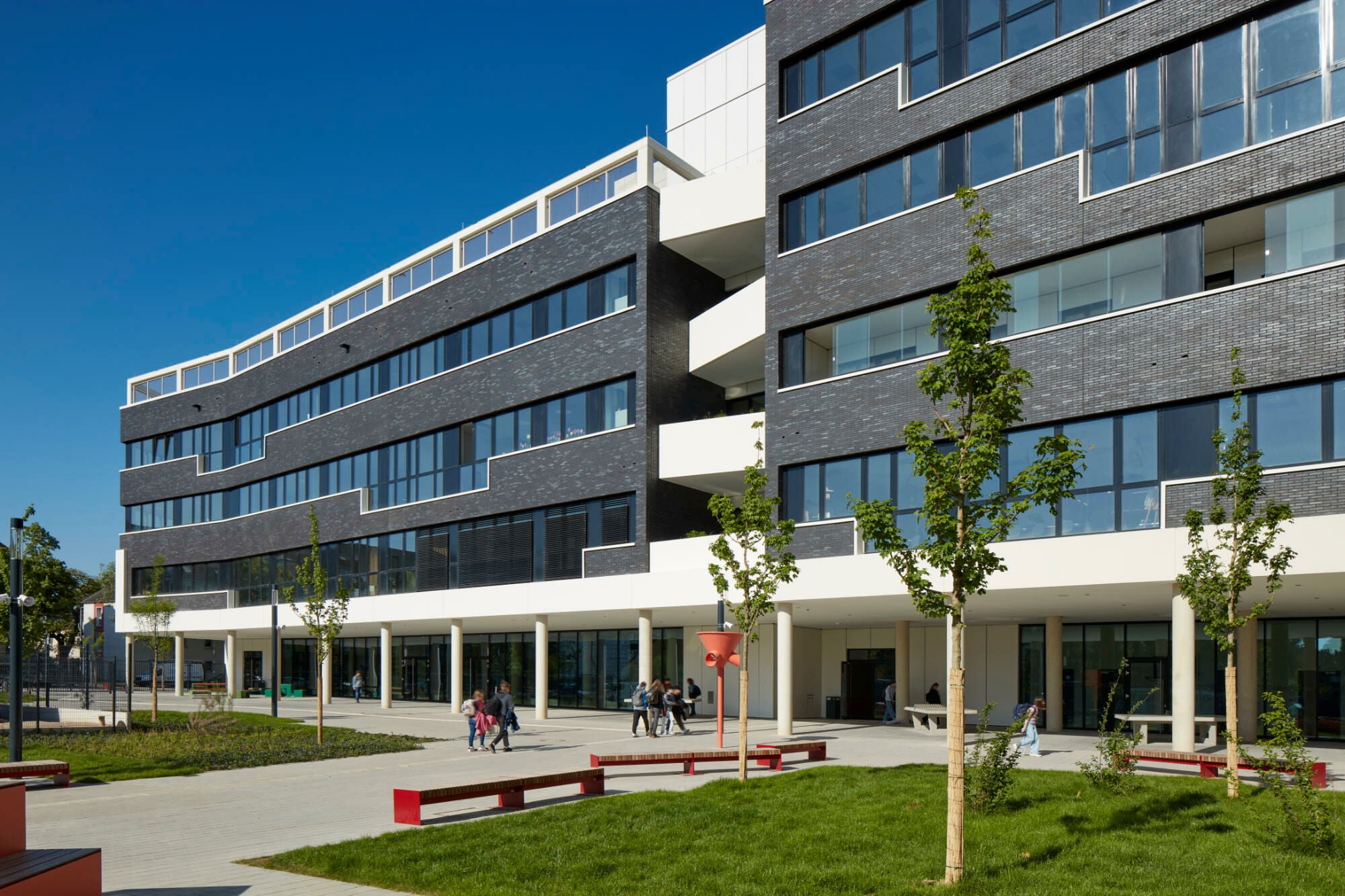 Der fünfgeschossige Schulbau ist wie ein Schiff organisiert: Zwei Geschosse mit wichtigen Flächen für die Gemeinschaft, darüber zu Jahrgangs-Clustern gruppierte Klassenräume, sowie ein zurückgestaffeltes, für alle nutzbares, oberstes Geschoss mit Fachklassen, Sportterrasse und Blick aufs nahe Wasser.
