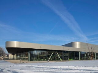 Das neue Hallenbad nach Plänen von 4a Architekten fügt sich durch die Höhenstaffelung und die abgerundeten Ecken in niedrigere Umgebungsbebauung ein.