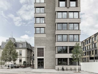 Um das brachliegende Restgrundstück zu nutzen, plante das Büro Boltshauser Architekten eine Verdichtung mit einem schmalen, achtgeschossigen Hotelneubau aus Lehmbausteinen.