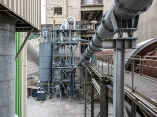 Die Pilotanlage besteht aus zwei Silos (links) sowie einer Zyklone und einer Brennkammer (Mitte). Rechts daneben sind der Drehrohrofen und die Leitung für die Klinkerkühlerabluft zu sehen.