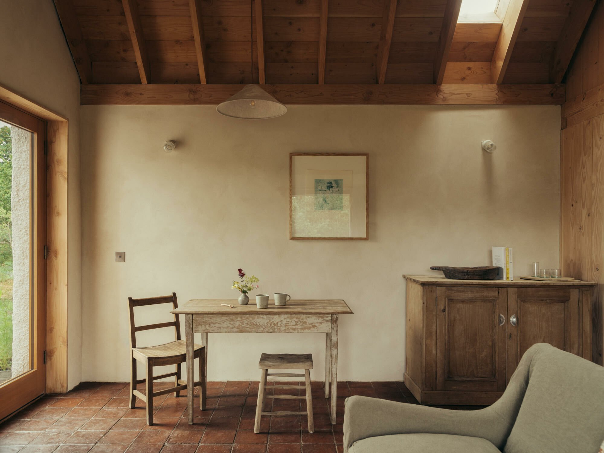 Zwischen locker angeordneten, deutlich größeren Häusern behauptet sich das schlichte Gebäude mit Wellblechdach auf einer kleinen Anhöhe und mit unverstelltem Blick auf die Bucht.