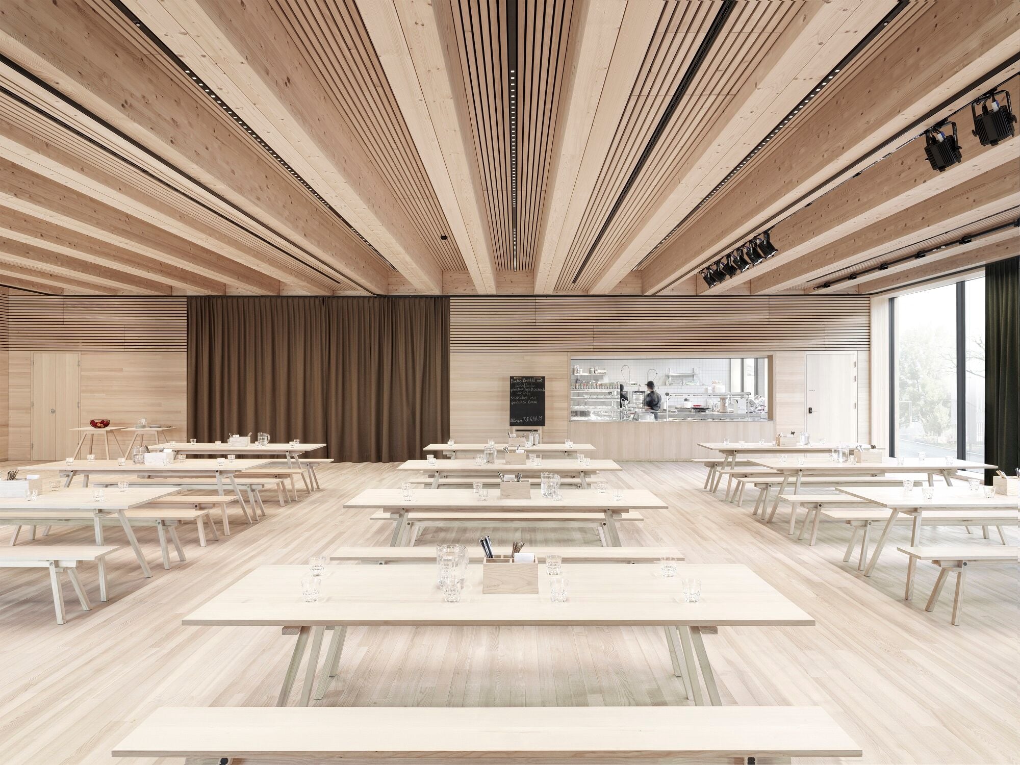 Aula im Gemeinschaftshaus: Große Fensterflächen schaffen eine lichtdurchflutete Atmosphäre.