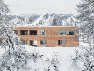 Das Architekturbüro dunkelschwarz plante die Erweiterung als schlichten Baukörper mit einer lebhaften Fassade aus Lärchenschindeln.