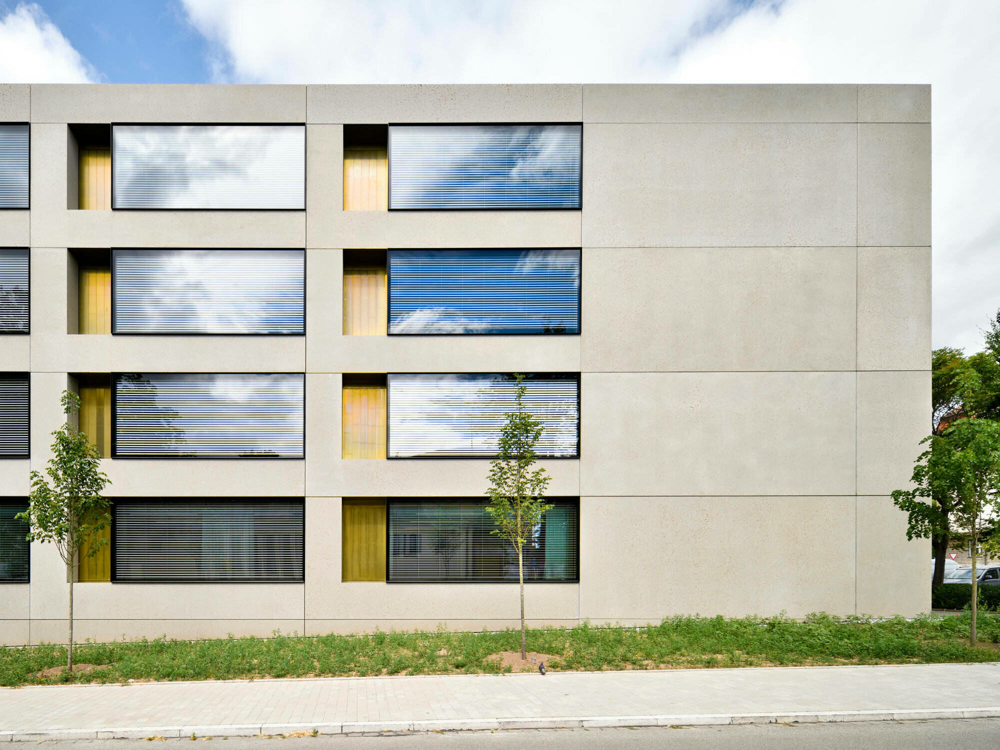 Außen liegen die Klassenräume – hinter einer Fassade aus großformatigen Betonfertigteilen, bündig eingesetzten Closed-Cavity-Fenstern und messingverkleideten Lüftungsklappen.