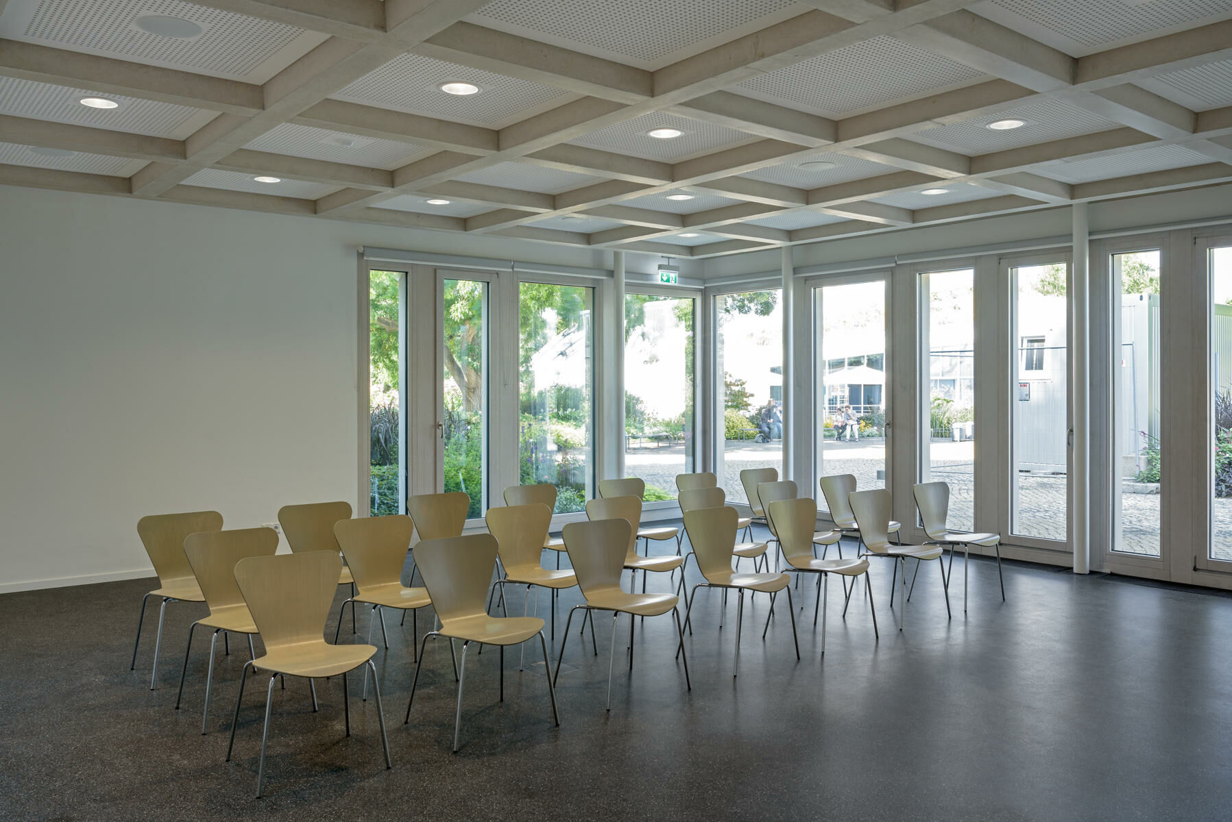 Eine stützenlos überspannende Sichtbeton-Kassettendecke prägt den Vortragsraum.