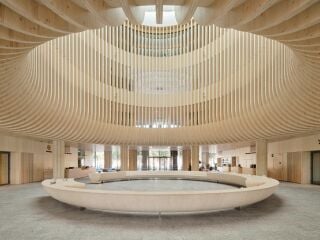 Der helle, viergeschossige Gebäudekomplex nach Plänen von Anttinen Oiva Architects erhebt sich an einem Hafenbecken.