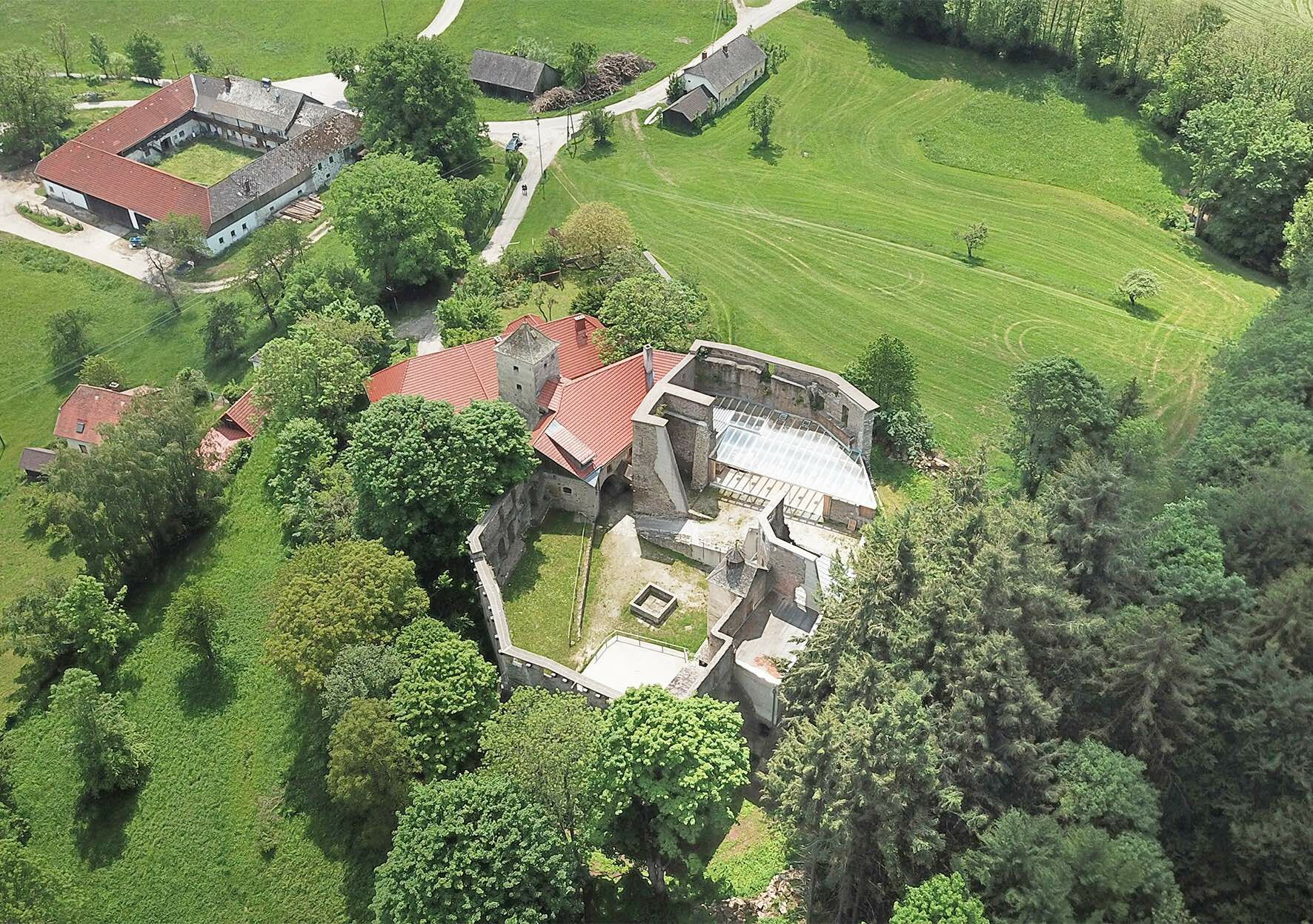 Blick von oben auf den Innenbereich der Anlage mit Betonabschlüssen an Mauerkronen und temporärer Überdachungsstruktur.