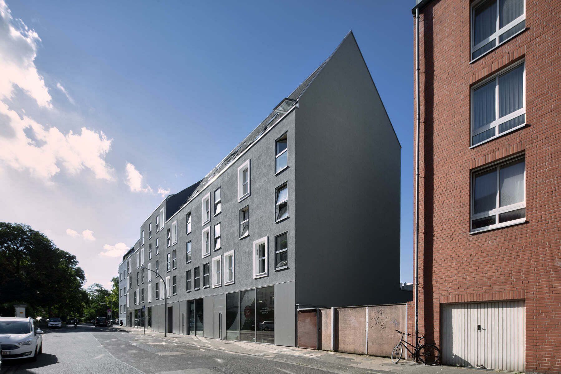Der langestreckte, fünfgeschossige Neubau mit Satteldach übernimmt die Höhen, Fluchten und Körnungen der umliegenden Blockrandbebauung. 