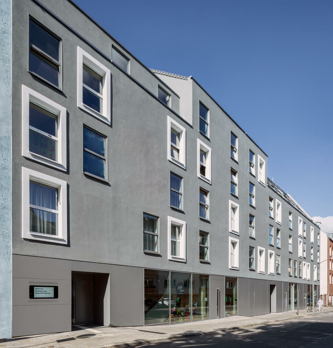 Im Erdgeschoss verankern eine Begegnungsstätte, ein Café sowie Verkaufsflächen für aufgearbeitete Recyclingprodukte das Haus im Quartier und schaffen niederschwellige Kontaktpunkte zwischen Bewohnerschaft und Nachbarschaft.