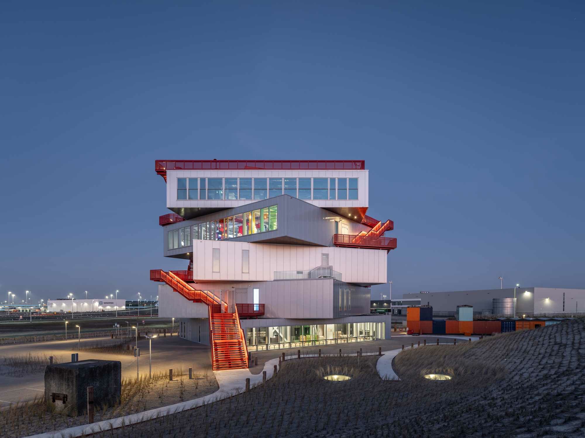 Eine öffentliche rote Stahltreppe wickelt sich um das Gebäude und leitet hinauf auf die Dachterrasse.