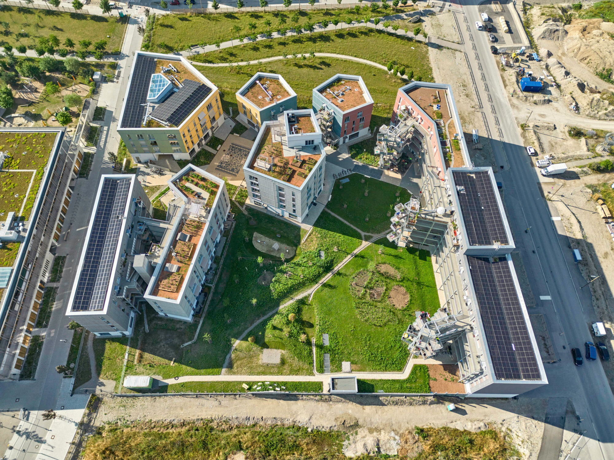 Auf der nahezu quadratischen Bebauungsfläche ordneten die Planenden vier heterogene Wohnkomplexe an: einen langen Wohnriegel und zwei Baukörper entlang der beiden Hauptstraßen sowie einen dreiteiligen Gebäudekomplex an der südlichen Grundstücksgrenze.