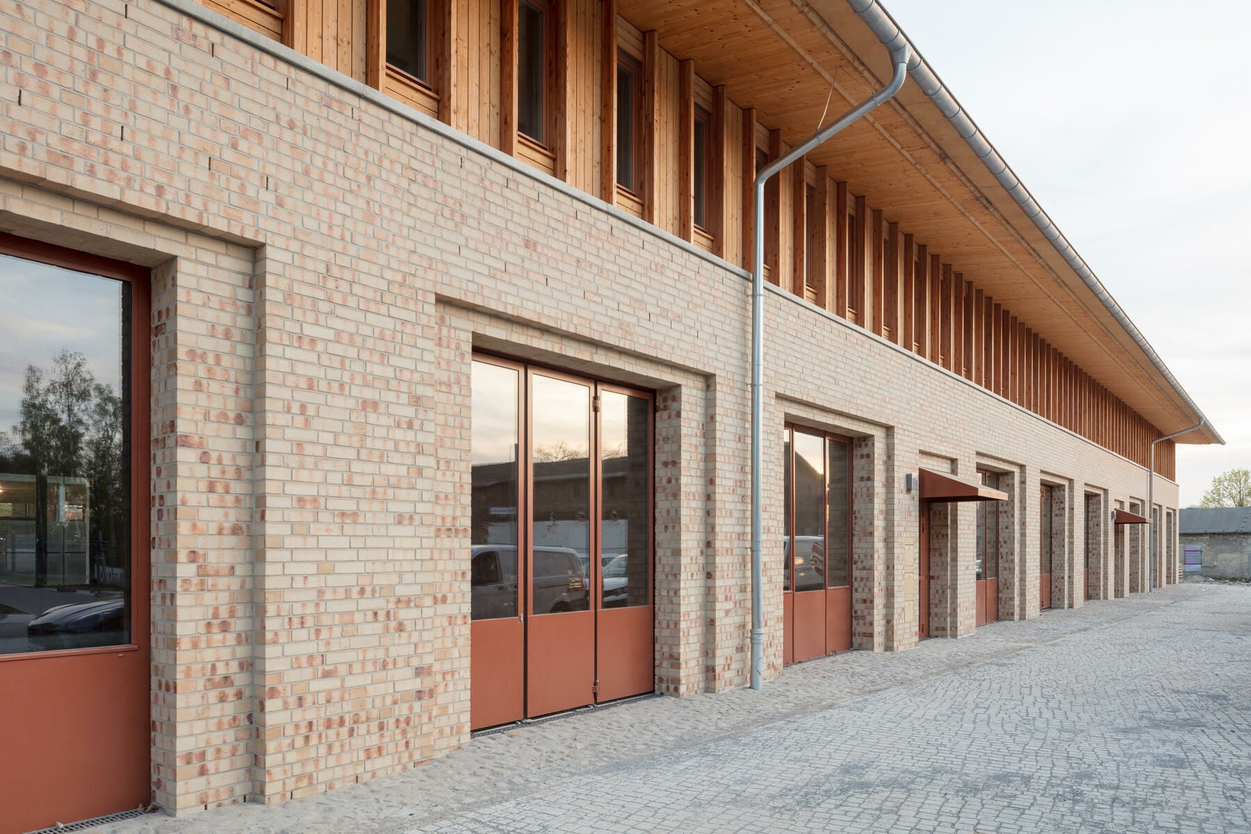 Ein massiver Mauerwerkssockel bildet die robuste Basis des Gebäudes, ein weit auskragendes Dach überspannt das Obergeschoss in Holzbauweise. 