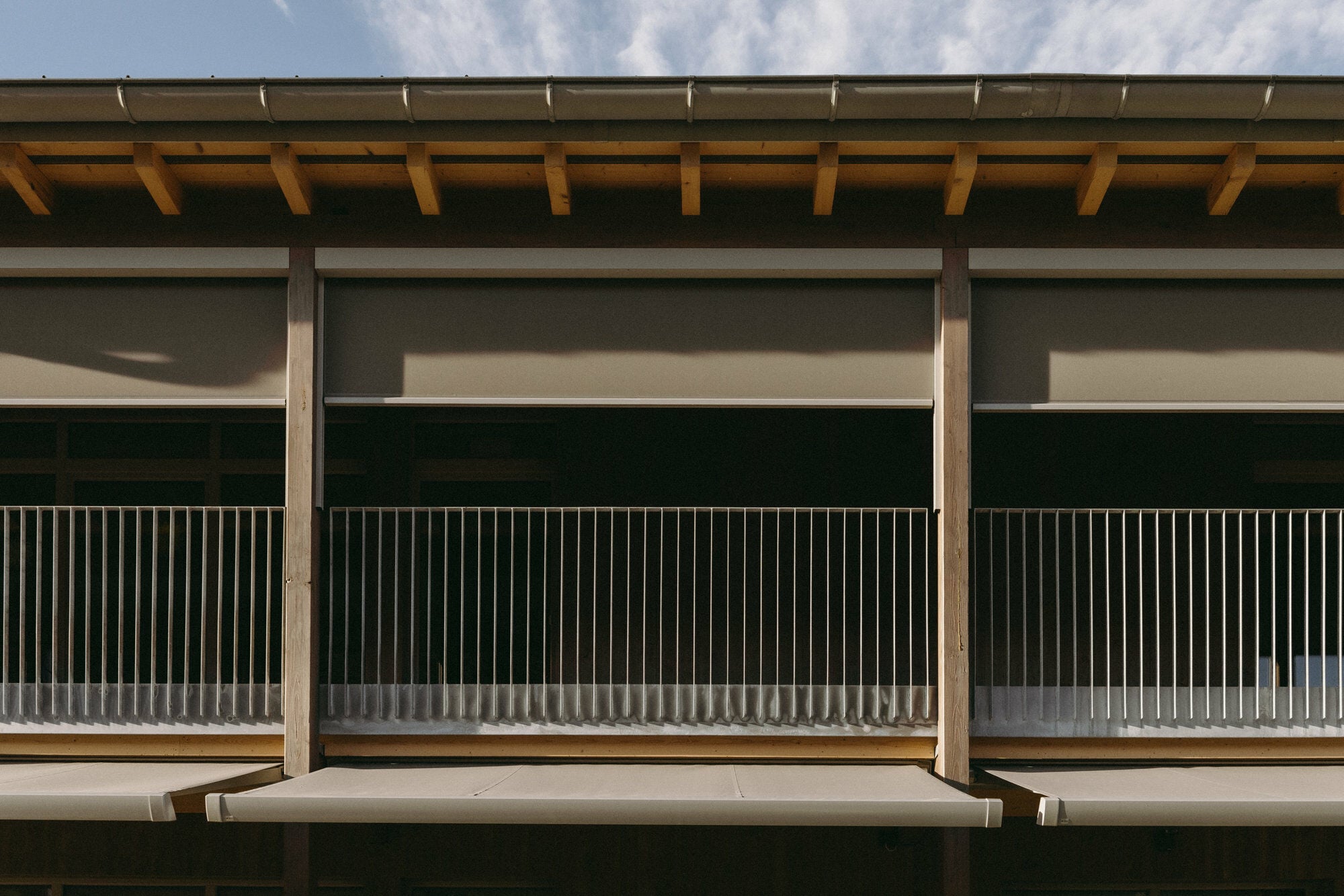 Die Terrassen im Erdgeschoss werden von Kassettenmarkisen verschattet, Senkrechtmarkisen verschatten die Balkonzone im Obergeschoss.
