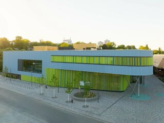 Das neue Main Bad Bornheim steht direkt neben der über 40 Jahre alten Eissporthalle mit ihrem markanten Dach und füllt den städtebaulichen Raum auf dem dreieckigen Grundstück effizient aus.
