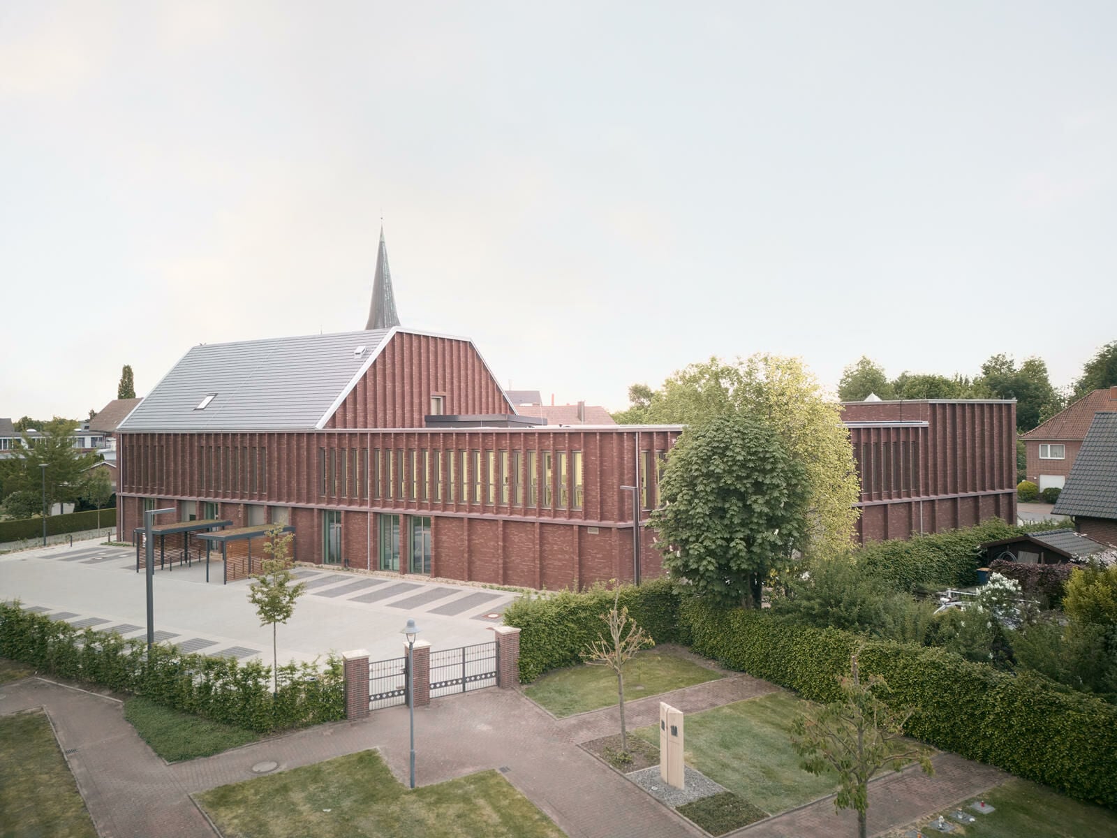 Der hintere Gebäudeteil knickt ein weiteres Mal ab und erhöht sich um ein halbes Geschoss, das mit einem regionaltypisch geneigten Dach und prägnanten Giebel zur Schulstraße abschließt.