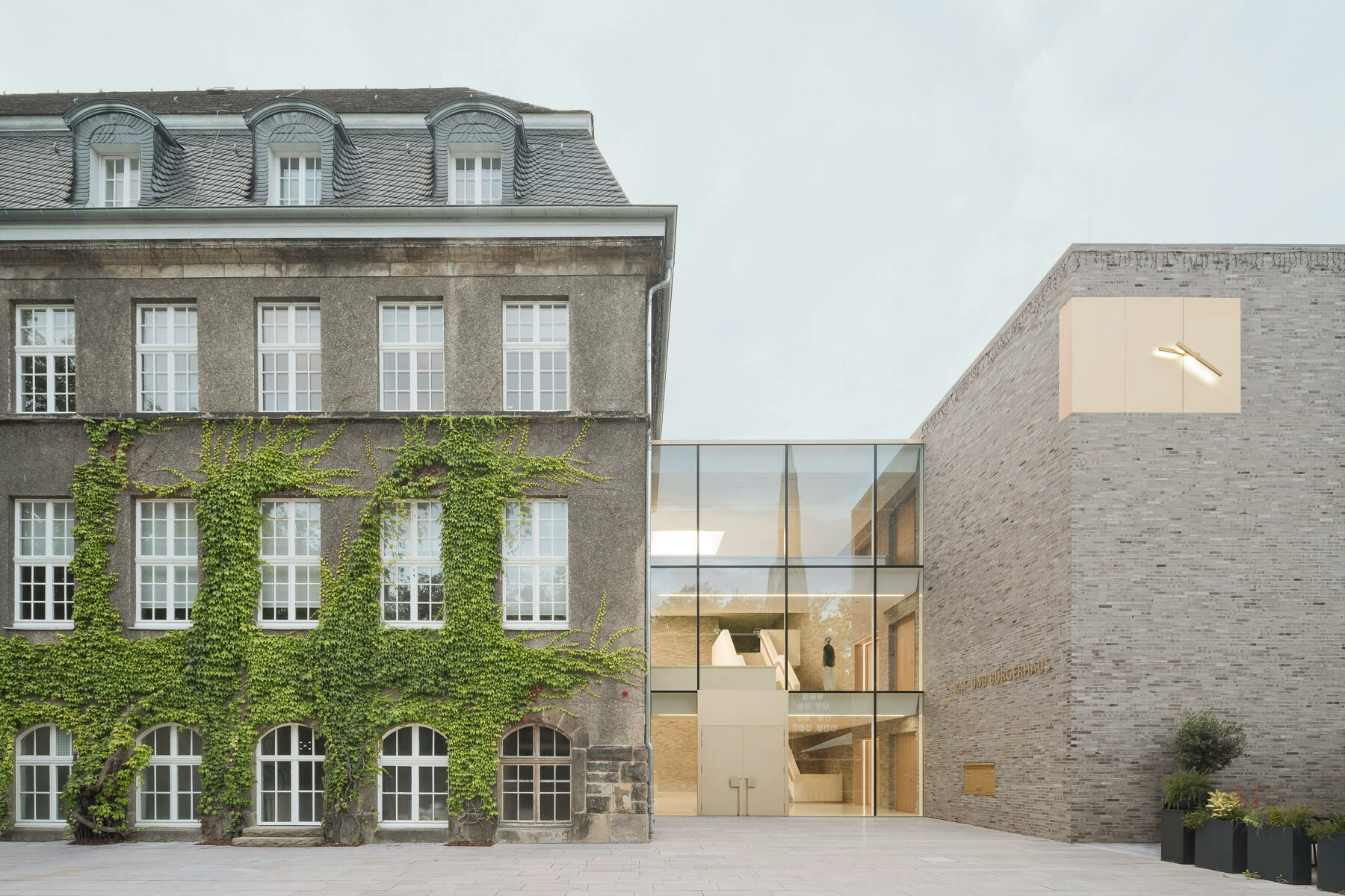 Das denkmalgeschützte Bestandsgebäude von 1915 wird nördlich und östlich durch einen winkelförmigen Neubau nach Plänen von Bez+Kock Architekten ergänzt.