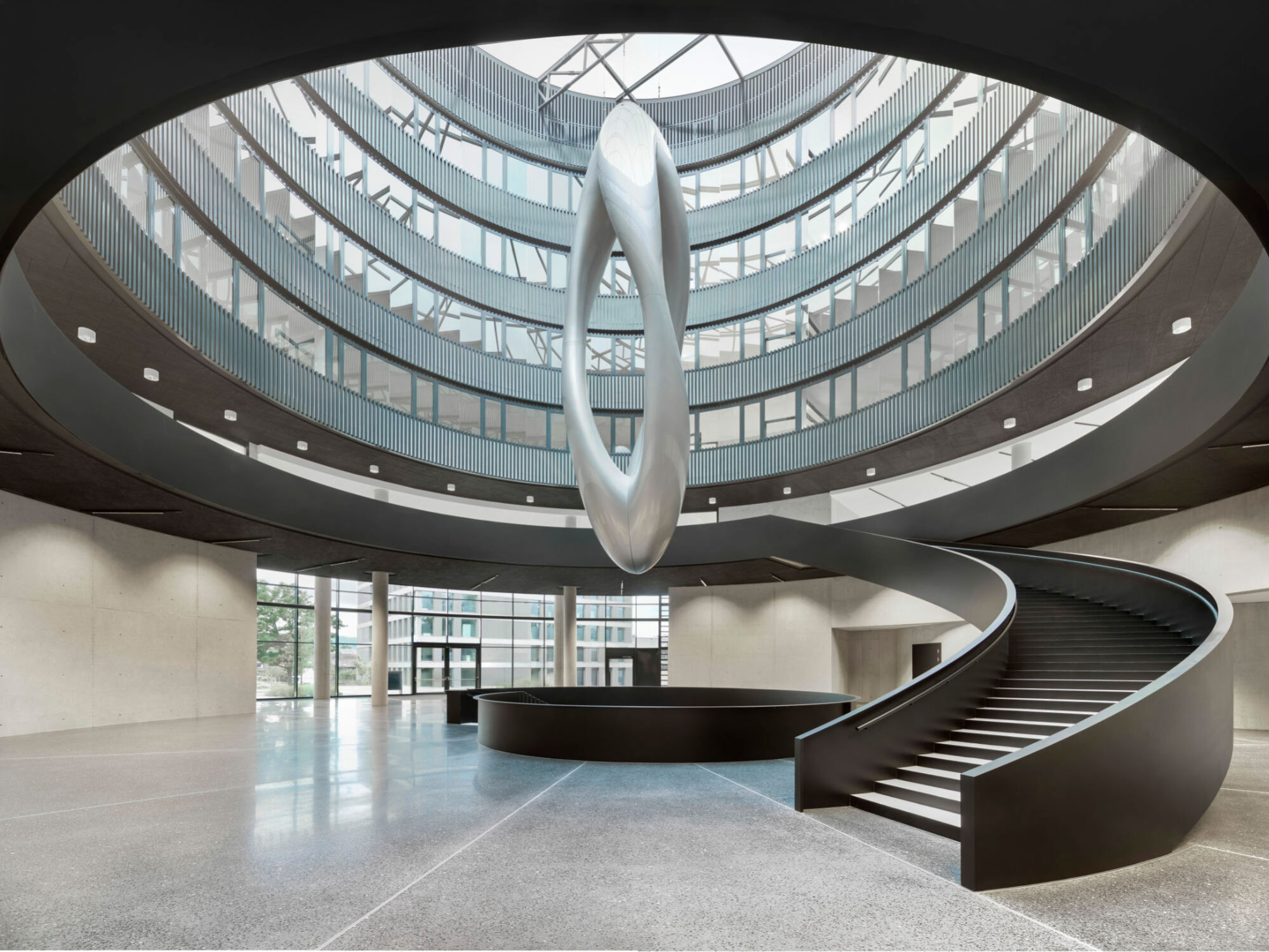 Das runde Gebäude hat in seiner Mitte ein Atrium, das alle Geschosse miteinander verbindet; direkt über Treppen in den öffentlichen Bereichen, visuell über Glasflächen in den Bürobereichen darüber.
