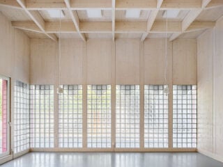 Die Holzwerkstatt nach Plänen von Bachmann Badie Architekten zieht mit einer dekorativen roten Fassade die Blicke auf sich.
