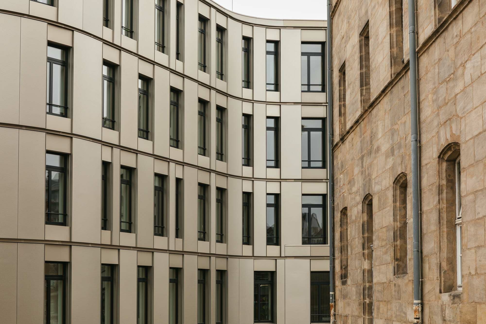 Die Gurtgesimse nehmen ein Gestaltungsmerkmal des benachbarten Altbaus auf und führen es fort.