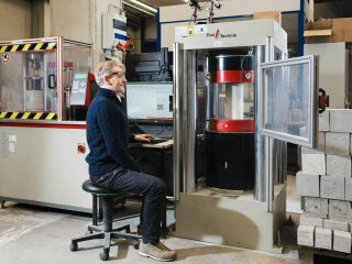 Professor Frank Dehn an einer Prüfmaschine der Materialprüfungs- und Forschungsanstalt Karlsruhe. Am KIT werden Betone mit Magnesiumsilikaten untersucht.
