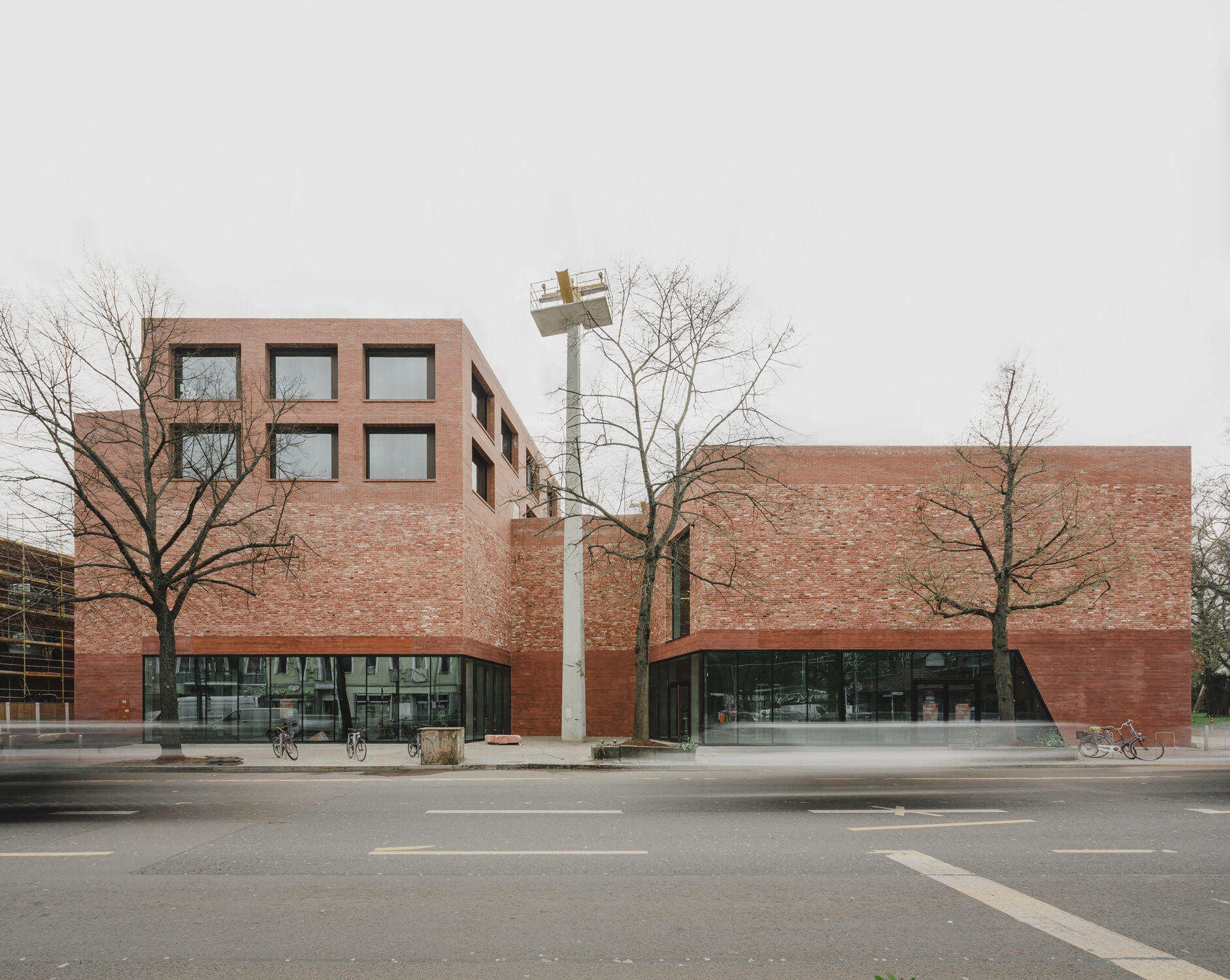 Für die Fassade wählten die Architekt*innen drei Materialien: rot pigmentierten Sichtbeton im Sockelbereich, darüber wiederverwendete Backstein-Ziegel und im oberen Bereich Neubrandziegel.