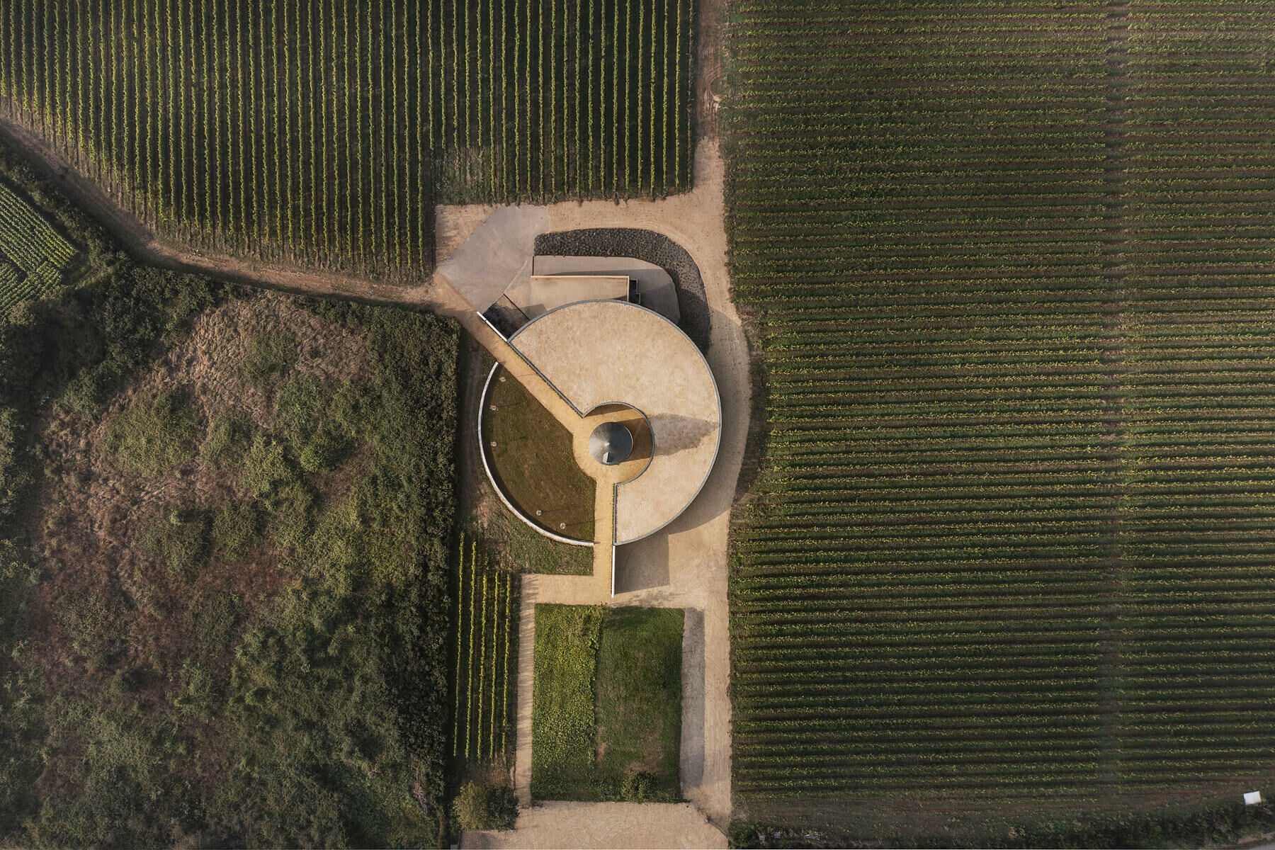 Wie ein massiver Sockel legt sich der ringförmige Neubau zu zwei Dritteln um eine historische, kleine Mühle. 