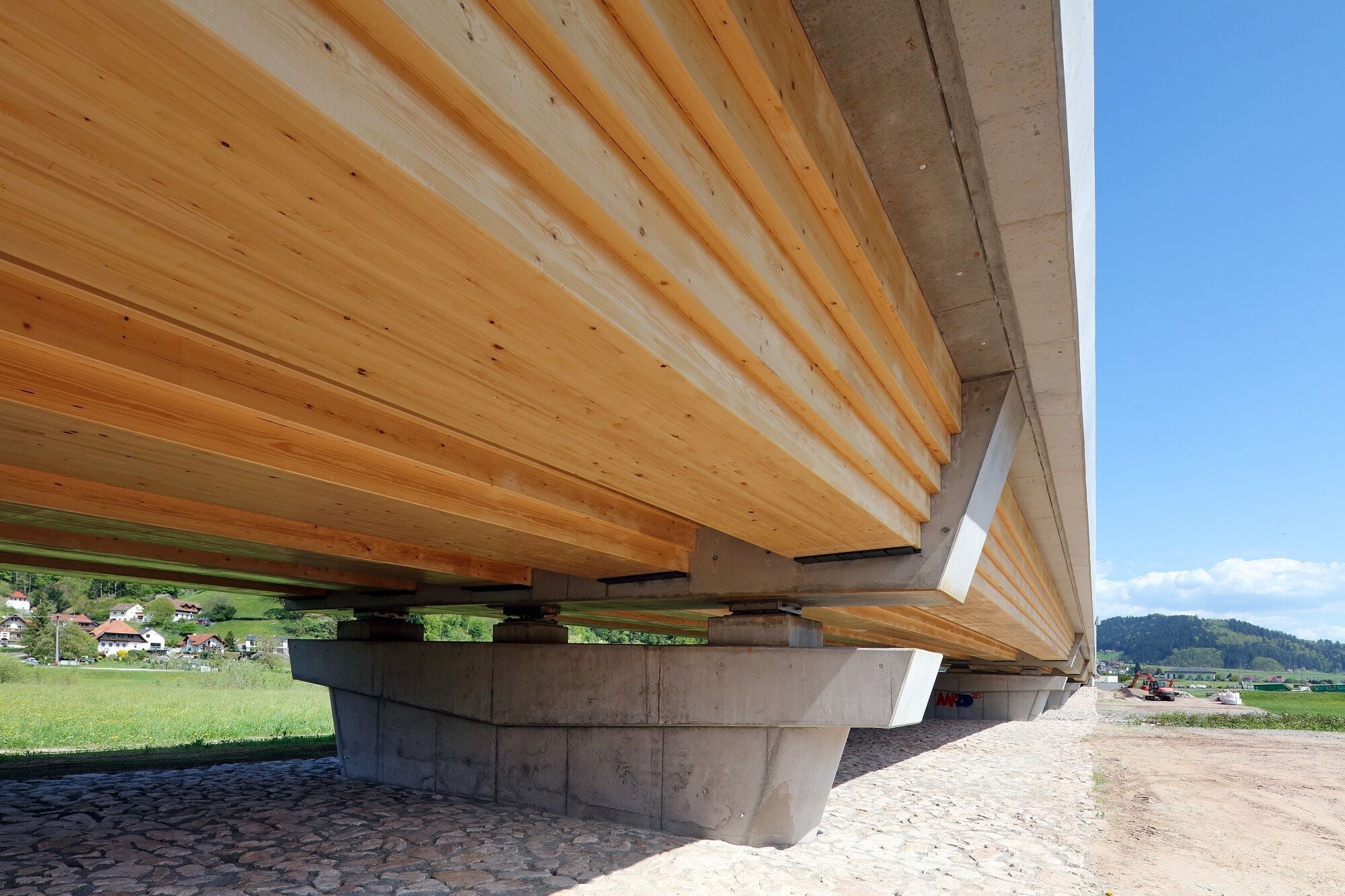 Die Brücke wurde als Pilotprojekt entwickelt, um die technische Machbarkeit von Holz-Beton-Verbundsystemen im Straßenbrückenbau unter Schwerverkehr nachzuweisen.