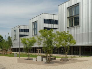 Der von sauerbruch hutton geplante, durchgrünte Campus mit zwei siebengeschossigen Wohnriegeln und dem Hochschulgebäude im Hintergrund