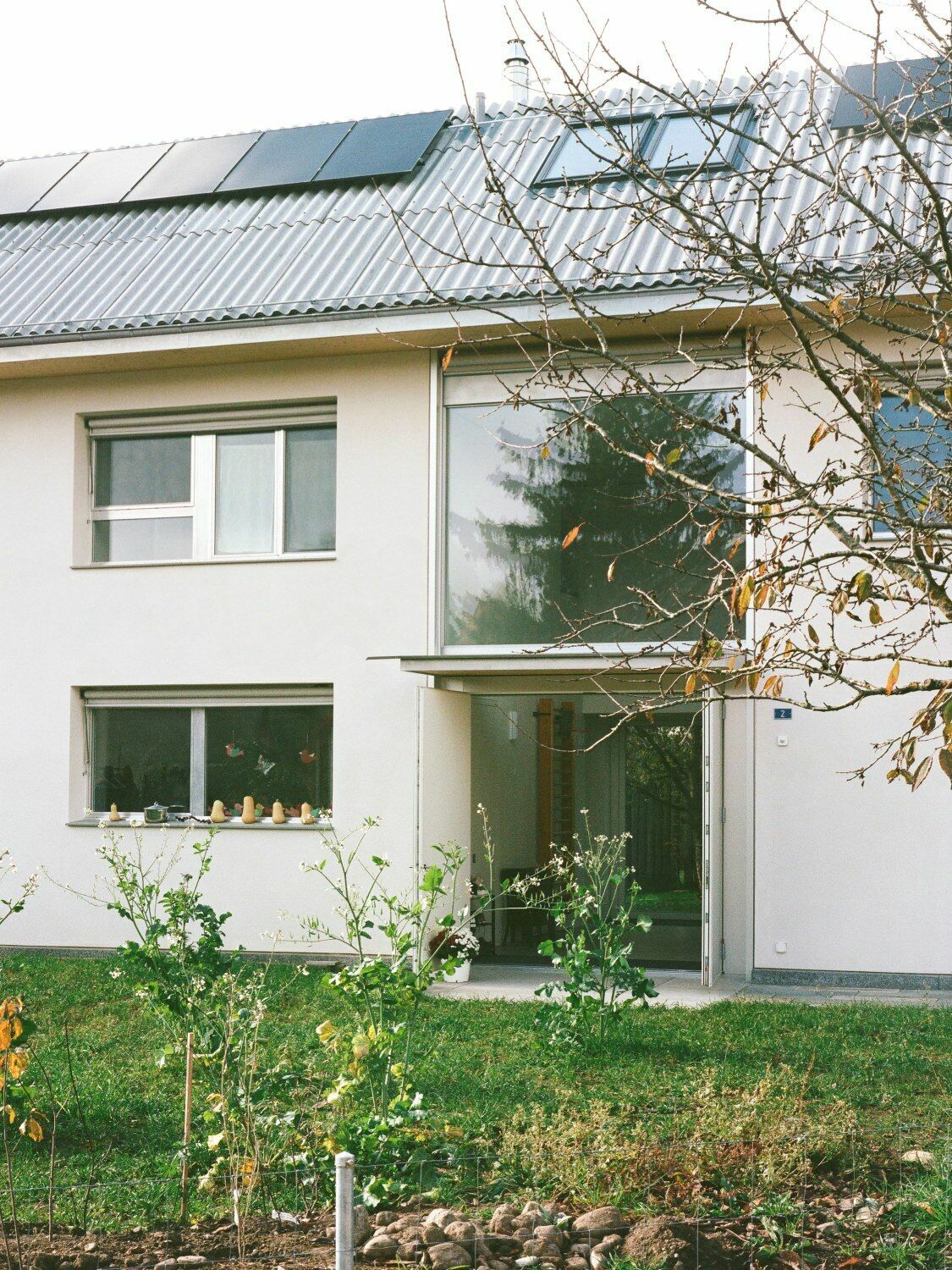Das Haus am Mühlesturz grüßt zur Straße mit einem voll verglasten Eingang.
