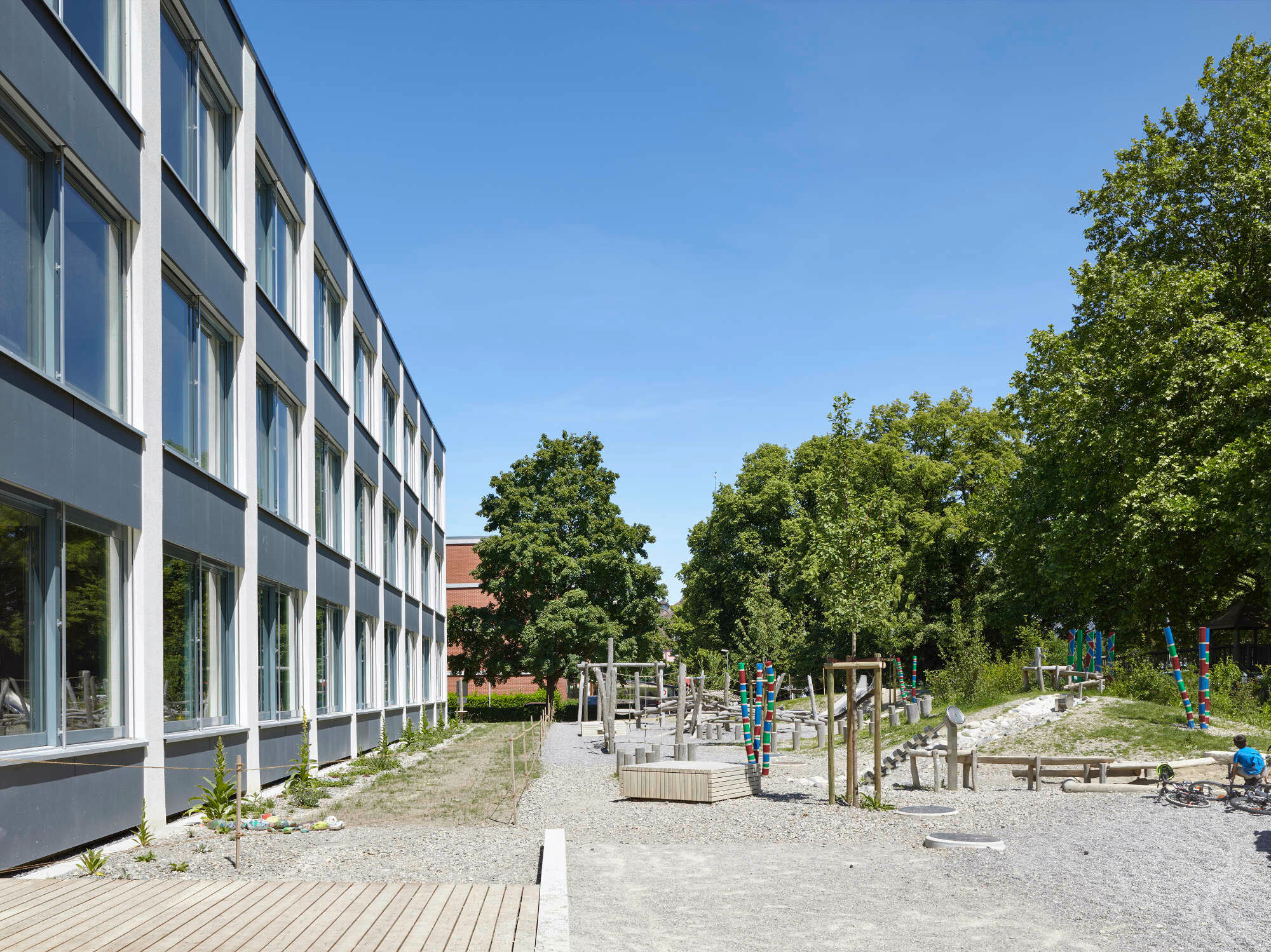 Der naturnahe Spielbereich schließt unmittelbar an die Südfassade an und erweitert den Schulalltag ins Freie.