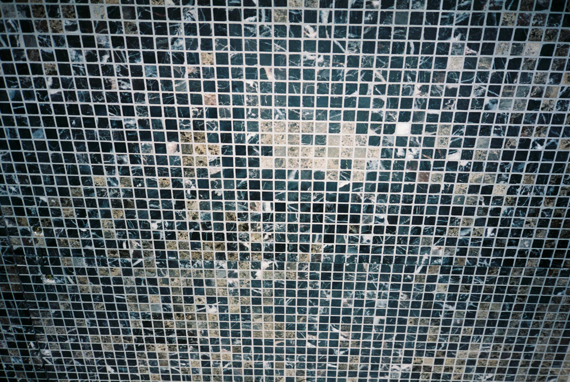Aus der Nähe löst sich das vermeintliche Betonbild in einzelne Mosaiksteine aus Naturmarmor auf.