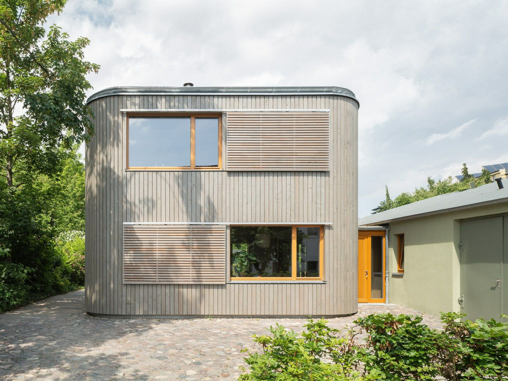 Südansicht des zweigeschossigen Neubaus, den ein schmaler Eingangsbau mit der ehemaligen Autowerkstatt verbindet.