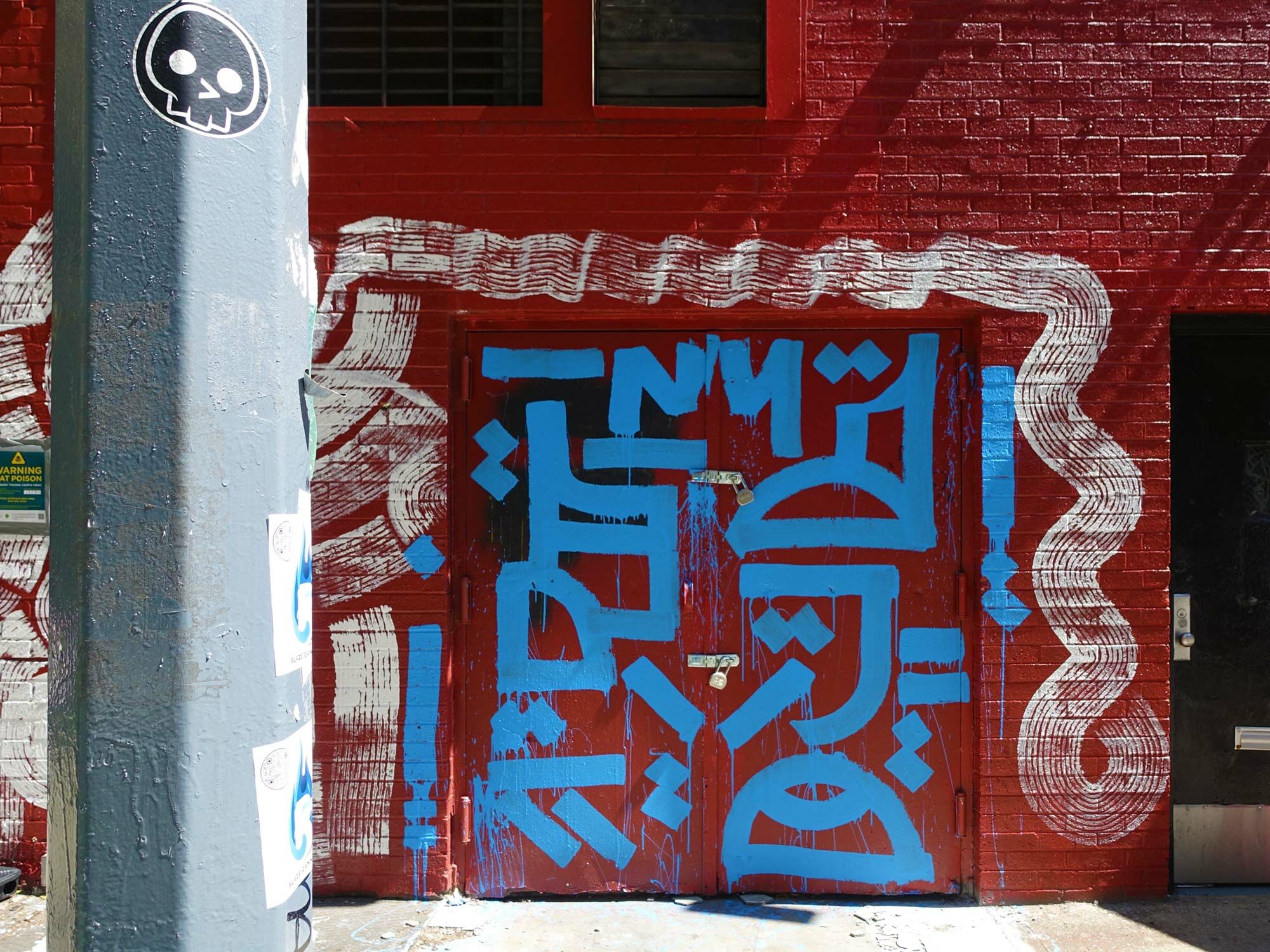 Die Grenzen zwischen Kunst im öffentlichen Raum, Kunst am Bau, Street Art und Graffiti sind oftmals fließend. Im Bild: Kalligraphie und Roll-Ons an einem Tor in NYC. 